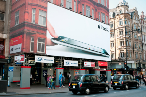 London, United Kingdom - April 25, 2011: Apple iPad 2 advertisement on a house facade in Oxford Street, London. Black taxis and pedestrians going past. Oxford Street is located at the heart of London and one of the main shopping areas in the city. The iPad 2 is Apple's leading tablet internet device.