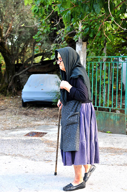 Parga, Greece - September 17, 2008: A traditionally dressed Greek lady walking through the town of Parga, Greece.   The lady is covering her head with a black head scarf and this generally indicates that she is a widowed lady.