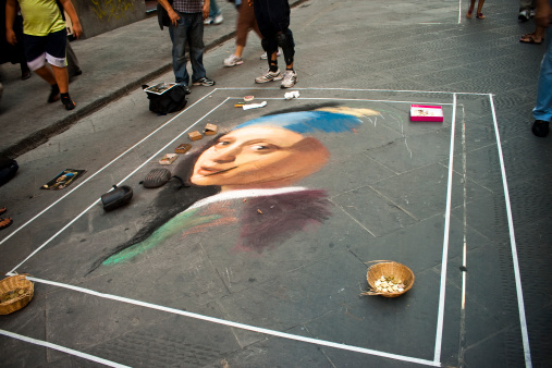 FLORENCE, ITALY - August, 11th 2010: Visitors looking at a half done famous painting \\'Girl with a Pearl Earring\\' by Jan Vermeer draws with chalk on tile at Florence walkway.