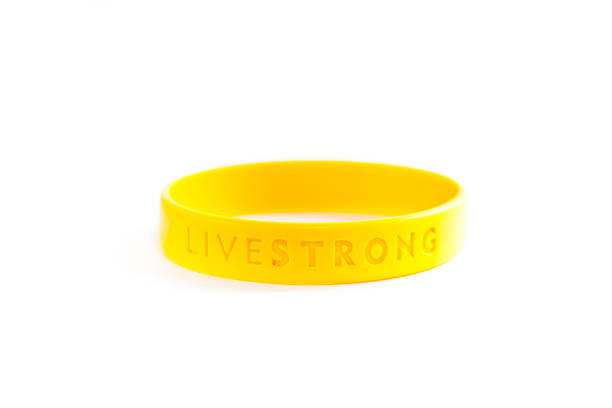 Livestrong Bracelet Manchester, UK - April 25, 2012: Livestrong Bracelet. A yellow silicone gel bracelet launched in May 2004 as a fund-raising item for the Lance Armstrong Foundation, founded by cyclist and cancer survivor Lance Armstrong. The bracelet itself was developed by Nike. lance armstrong foundation stock pictures, royalty-free photos & images