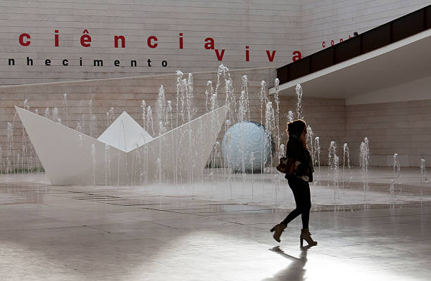 Lisbon, Portugal - December 17, 2011: A woman passed outside of a science museum in Lisbon. This is the entrance of the Pavilion of Knowledge - Ciencia Viva (Pavilhao do Conhecimento). Formerly it was during the Expo 1998 an exhibition hall for foreign countries. In background is a beautiful fountain and a little ship which remembered in history of the of Portugal as maritime and seagoing nation.