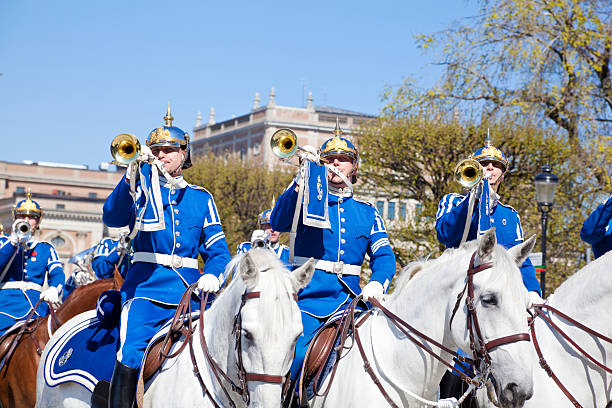 Stockholm, Sweden- May 6, 2011: Mounted soldiers of the Cavalry Battalion (Royal Guards) and an army band in their characteristic blue uniforms and piked helmets   on way to the Royal castle in Stockholm and changing of the guards. They also form a military band.  Beautiful white and brown horses. Those mounted guards ride between April and August and are a great tourist attraction.
