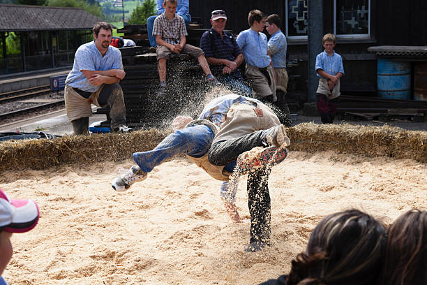Boltigen, Switzerland - September 3, 2011: Two young men wrestling in Boltigen, Switzerland.  One young man is in the process of wrestling his opponent to the ground, forcing him to land on his back, which signifies the end of the match.  The wrestling ring has been set up next to the train station in the village of Boltigen and is part of the Farmer's market there.Boltigen is located in the Bernese Oberland, Switzerland  in the Simmental where the road from the Jaun Pass reaches the floor of the Simmen valley. It is an agricultural village, and periodically holds a farmer's market on the square next to the train station. The market is frequented primarily by local people.