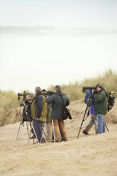 Titchwell, United Kingdom - January 7, 2011: A group of bird watchers stand among the sand dunes with binoculars and digiscopes.