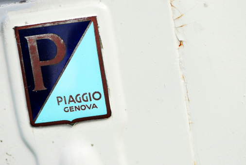 Borgosesia, Italy - September 11, 2011: Piaggio Genova old logo on white Piaggio Vespa scooter parked in the street.