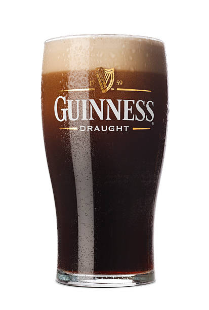 Pint of Guinness Dublin, Ireland - March 16, 2011: Freshly pulled pint of Guinness with its foamy head in a traditional pint glass. A world wide famous Irish stout originated in the brewery of Arthur Guinness (1725–1803) at St. James's Gate, Nowadays, Guinness Stout is brewed under licence internationally in several countries, including Nigeria, the Bahamas, Canada and Indonesia. However the unfermented but hopped Guinness wort extract is always shipped from Dublin and blended with beer brewed locally. amber black photography stock pictures, royalty-free photos & images