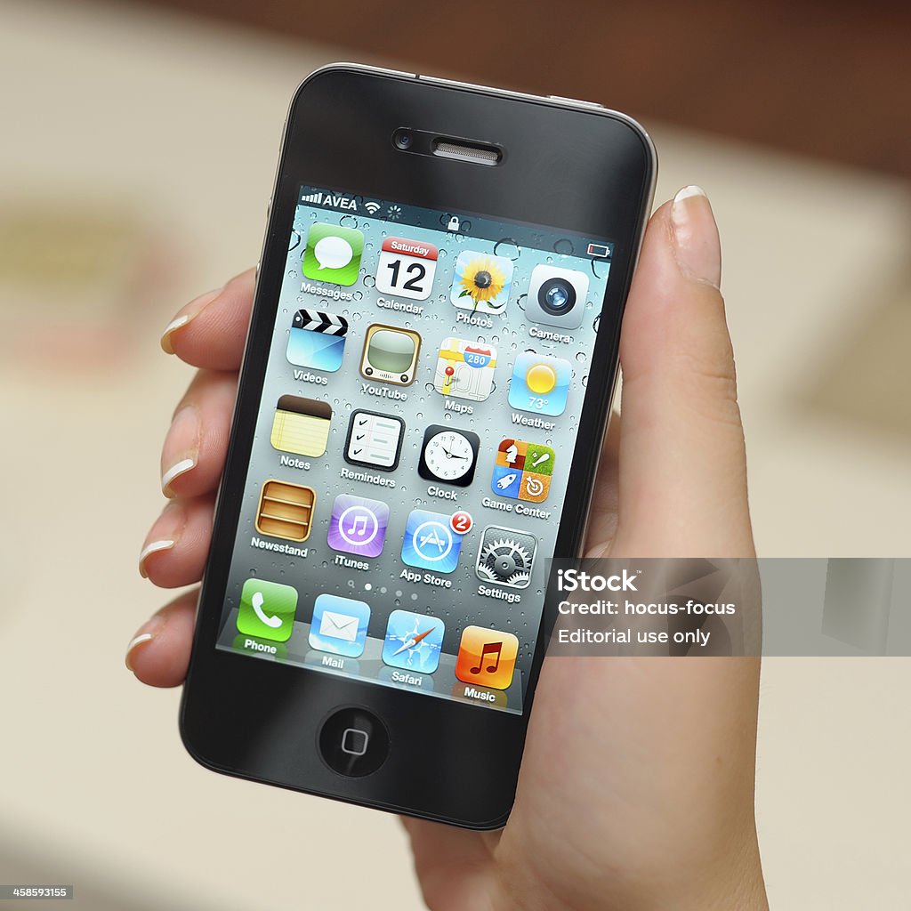 Holding iPhone 4 Astanbul, Turkey - November 12, 2011: Woman holding Apple iPhone 4 displaying homescreen. The iPhone 4 is a touchscreen slate smartphone and the fourth generation iPhone, developed by Apple Inc. Adult Stock Photo