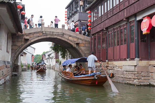 Water Town Zhouzhuang, China Zhouzhuang, China - July, 15th 2007 : Villagers row boats at a canal, many tourists sitting on the boat and go sightseeing in Zhouzhuang Town of Kunshan City, Jiangsu Province, China. Some tourists are standing at the bridge. Zhouzhuang, first built around 1,000 years ago, is one of the most famous water townships in China, noted for its profound cultural background, the well preserved ancient residential houses, the elegant watery views and the colourful local traditions and folklore. Sixty percent of Zhouzhuang\\\'s structures were built during the Ming and Qing Dynasties from 1368 to 1911. grand canal china stock pictures, royalty-free photos & images