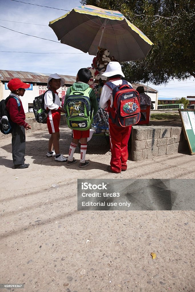 Bolivian schoolchildren buying sweets Copacabana, Bolivia - May 29, 2013: Group of four Bolivian schoolchildren wearing rucksacks leaving school for the day. They are buying sweets from a street trader Bolivia Stock Photo