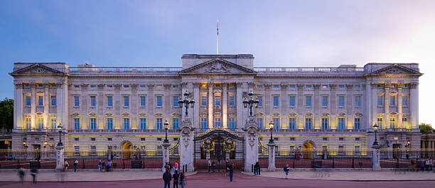 London, United Kingdom - August 7, 2011: Tourists and locals gather around the entrance to Buckingham Palace, home of Queen Elizabeth II, just after sunset.