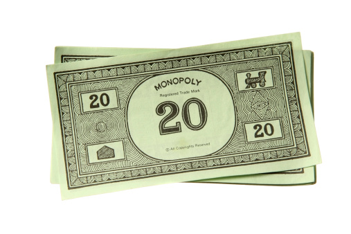London, United Kingdom - August 4, 2011: Monopoly game money. Monopoly is a board game named after the concept of dominating a market, a monopoly. Players take turns to move around a board buying property and paying and receiving rent.