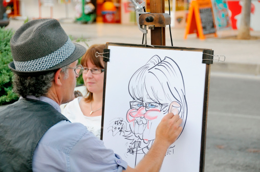Alcudia, Spain - June 28, 2011: Caricature Artist drawing a woman in Alcudia, Mallorca. Artists line the resort during the summer for tourists to take back as souvenirs.