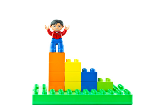 Suffolk, Virginia, USA - April 12, 2011: Studio shot of a conceptual bar graph made with Lego brand Duplo toy blocks, with a Lego man standing on the top bar with his arms outstretched. This is a horizontal format.