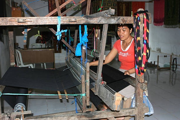 Tenganan, Bali, Indonesia aa March 27, 2008 : Balinese woman at a weaving machine in the village of Tenganan. Tenganan is the most famous Bali Aga (original Balinese) village and is known for itsaa double weave ikat, called a geringsing, the only such place to be found in South Eastern Asia and one of only 3 in the world.