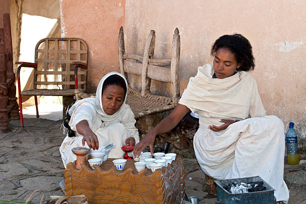 Axum, Ethiopia - February, 6 2011: Two young Ethiopian woman in traditional clothing woman are preparing a traditional coffee ceremony. This ritualised ceremony is an important part of the Ethiopian culture.