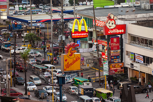 Manila, Philippines - April 18, 2012: View over Makati Avenue in the centre of Metrolopitan Manila, Signs for the fast-food chains Jollibee, McDonalds and Andok's are prominent in the image. Many people can be seen on the sidewalks.