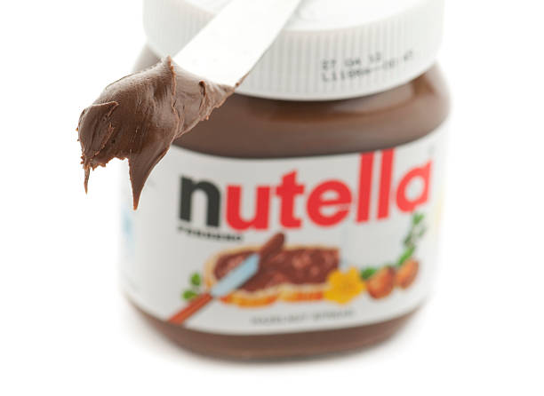 Knife with Nutella in front of jar stock photo