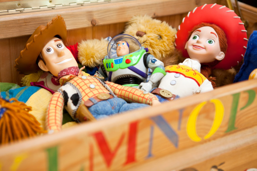 East Sussex, United Kingdom - April 24th 2011: Three original children\'s toys, Woody, Buzz Lightyear and Jessie, modelled on the characters from the popular Disney/Pixar Toy Story film franchise lying in a wooden toy box with other toys.