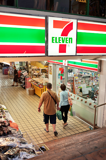 Chiang Mai, Thailand - March 31, 2011: Two people approach the entrance of a 7 Eleven store in the basement of a building in the Night Bazaar area of Chiang Mai, Thailand. 7 Eleven  franchises located are in 18 countries with approximately 6,000 stores in Thailand.