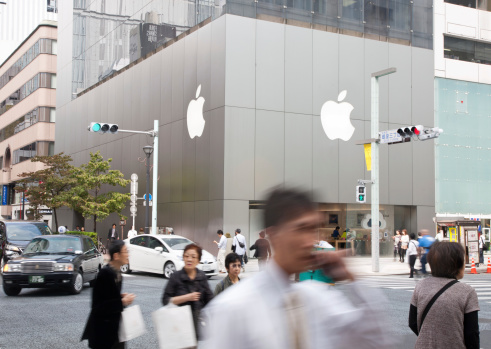 Ginza, Tokyo, Japan - October 17, 2011: Across the street view  of Apple Store with shoppers holding shopping bags and an office worker on the phone in fashionable Tokyo shopping district of Ginza.