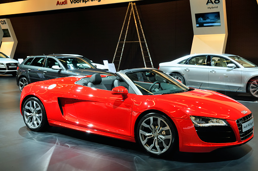 Amsterdam, The Netherlands - April 12, 2011: Red Audi R8 Spyder on display at the 2011 Amsterdam Motor Show. There are other Audi models in the background, including the A8 and A3. The 2011 Amsterdam motors how was running from April 12 until April 23, in the RAI event center in Amsterdam, The Netherlands.