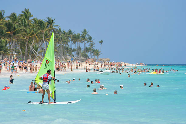 Punta Cana, Dominican Republic - April 8, 2007: Tourist trying wind surfing at a busy Punta Cana beach with terrible technique. This is, after swimming, the second most popular activity by the many beach visitors on vacation, despite its hard learning curve.