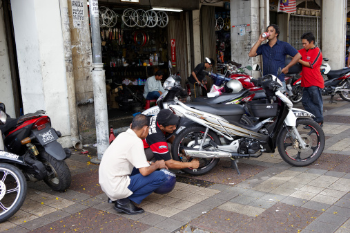 Kuala Lumpur, Malaysia - October 3, 2010: mechanic repair a motorbike in a repair shop in Jalan Tuanku Abdul Rahman, in Chow Kit District, with the vehicle owner watching closely.