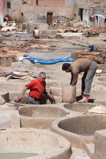 Marrakech, Morocco - March 19, 2011: People working at the leather tanneries. A hard and unhealthy labour with chemicals in the open air. Traditionally at the city walls because of the bad smell it produces.