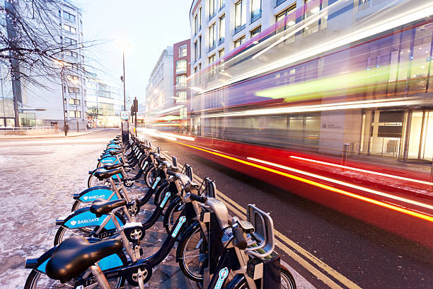 Boris Bikes London, UK - December 3, 2010: A row of Barclay Cycle Hire bicycles, known locally as "Boris Bikes," locked into a bicycle rack in the City of London, UK. A red London bus is passing by. boris bus stock pictures, royalty-free photos & images