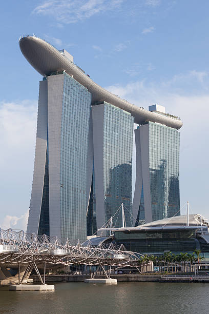 Singapore City, Singapore - May 19, 2012: People at the Helix Bridge near the Marina Bay Sands. Marina Bay Sands, designed by Moshe Safdie, is the integrated resort in Singapore. It is world's most expensive casino property. It become a famous tourist attractions in Singapore.