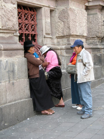 Quito, Ecuador - November 20, 2008: Group of four local Ecuadorians, three women and one man stand talking in the street at a Quito ATM machine