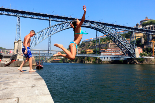 Oporto, Portugal - June 29, 2011: Young boys and girls sunbathing and jumping in Douro river during the summer.