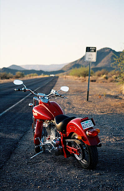 Arizona, USA - May 1, 2002 : Late afternoon in Arizona, and an Indian Chief Classic motorcycle sits at the side of a road that stretches off into the distance. The headlights of an approaching car can be seen further up the road.