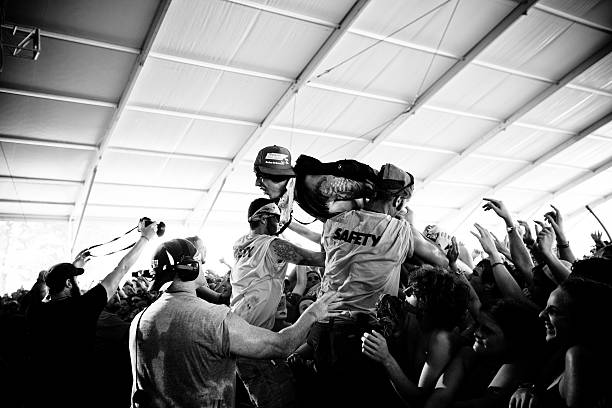 Wild fan crowd surfing Manchester, United States - June 10, 2011: A wild fan crowd surfing in and yelling as security grabs him. Bonnaroo Music and Arts Festival. mosh pit stock pictures, royalty-free photos & images