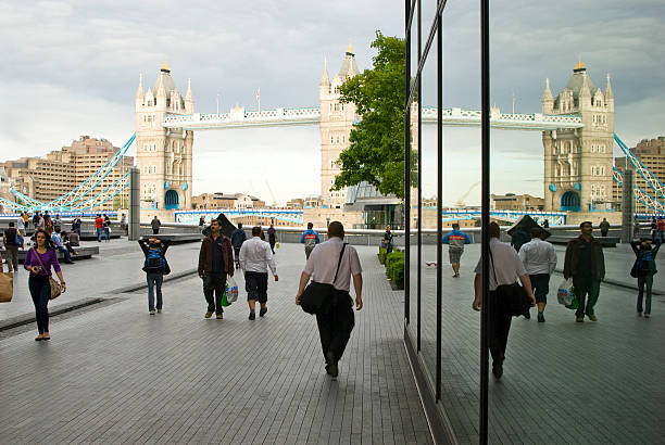 Tower Bridge London London, United Kingdom - May 08, 2011: Tourists walk along the Thames, the Tower Bridge in the background. A mirror image is in the business building on the right launch tower stock pictures, royalty-free photos & images