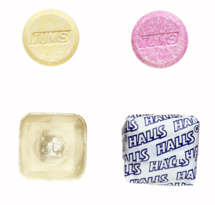 Truro, MA USA - October 21, 2011: Two tablets of TUMS and two pieces of Halls cough drops. TUMS is an antacid made of sucrose manufactured by GlaxoSmithKline in St.Louis, Missouri, USA. Halls is the brand name of a popular mentholated cough drop manufacturer are sold by Cadbury headquarter in Northfield, Illinois, United States.