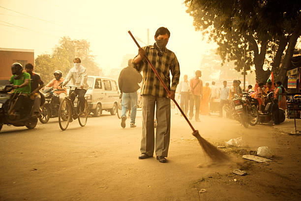 cleaning the road in India New Dehli, India - November 12, 2010:  Crowded and dirty street, worker cleaning the road. street sweeper stock pictures, royalty-free photos & images