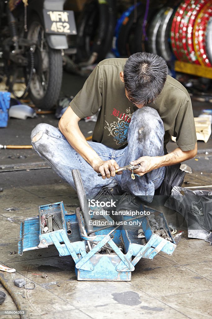 Repairing Motorbikes Kuala Lumpur, Malaysia - October 3, 2010: mechanic repairing motorbike in a repair shop in Jalan Tuanku Abdul Rahman. In foreground a tool-box with mechanical tools. Adult Stock Photo