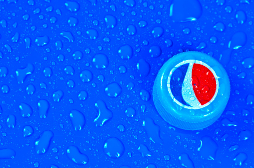 Alanya, Turkey - May 01, 2012: Pepsi Cola bottle cap on blue and wet surface. Studio shot. Pepsi is a carbonated soft drink that was originally created in 1898.