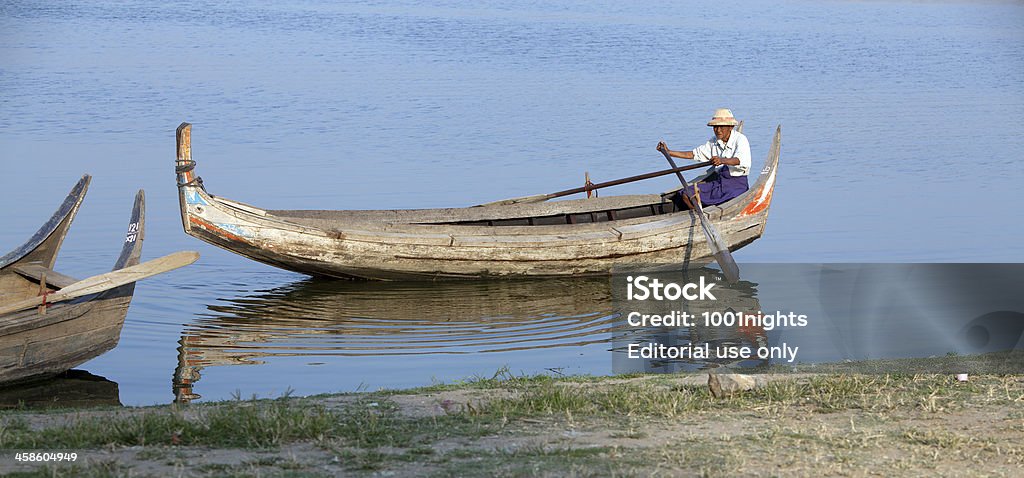 Along the Irrawaddy, Myanmar Sagaing, Myanmar - February 19, 2011: An old man rows his boat alone, along the waters of the Irrawaddy river. Sagaing, located on the Ayeyarwady/Irrawaddy river, is a famous religious center with many Buddhist monasteries. The pagodas and monasteries are located along the numerous hills running parallel to the river. Active Seniors Stock Photo