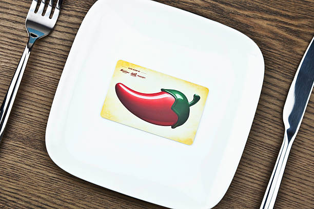 Suffolk, Virginia, USA - May 24, 2011: A horizontal studio shot of a place setting with a white china plate and knife and fork. In the middle of the plate is a Chili's Restaurant gift card.