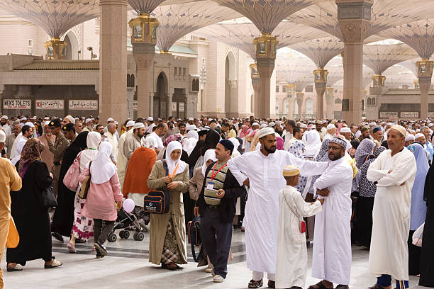 Medina, Saudi Arabia - April 15, 2011: Muslim pilgrims walking in the courtyard of Masjid al-Nabawi ( Prophet's Mosque ) after the noon prayer. As the final resting place of the Prophet Muhammad, it is considered the second holiest site in Islam by Muslims (the first being the Masjid al-Haram in Mecca).