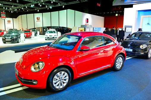 Brussels, Belgium - January 10, 2012: Red Volkswagen New Beetle on display during the Brussels motor show. People in the background are looking at the cars.