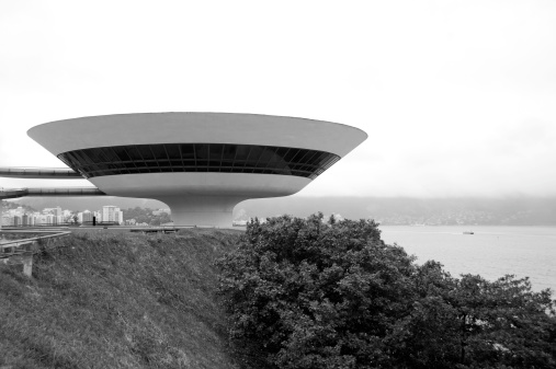 Niteroi, Brazil - June 26, 2011: The NiterAi Contemporary Art Museum (Museu de Arte ContemporAnea de NiterAi aa MAC) is situated in the city of NiterAi, Rio de Janeiro, Brazil, and is one of the cityaas main landmarks. It was completed in 1996.Designed by Oscar Niemeyer with the assistance of structural engineer Bruno Contarini, who had worked with Niemeyer on earlier projects, the MAC-NiterAi is 16 meters high; its cupola has a diameter of 50 metres with three floors. The museum projects itself over Boa Viagem (aBon Voyage,aA aGood JourneyaA), the 817 square metres (8,790 sq ft) reflecting pool that surrounds the cylindrical base alike a flower,aA in the words of Niemeyer.
