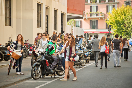 Milan, Italy - October 01, 2011: College students hanging around on Campus after school. Young man sitting on a vespa.