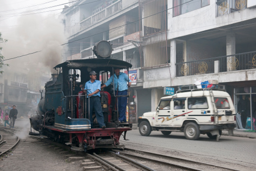 Ghoom, Darjeeling, India - May 18th, 2012: Steam engine of old Toy Train turning in Goom city, Darjeeling District(West Bengal); engine drivers on the engine, people walking.