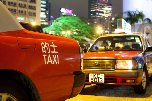 Hong Kong, China - December 25, 2010: Taxis waiting in line in Nathan street while people are walking around this main shopping area of Tsim Sha Tsui