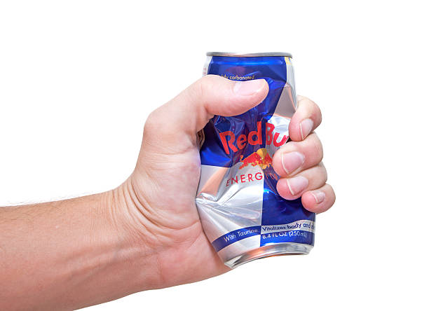 Redbull Crushed Can Nashville, Tennessee, USA - September, 2nd 2011: A can of Red Bull energy drink in it\'s iconic blue and silver can being squeezed and crushed by a mans hand, photographed against a white background. energy drink photos stock pictures, royalty-free photos & images