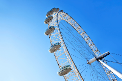 London, England - May 04, 2011: The famous London Eye ferris wheel on the bank of the river Thames against blue sky. London Eye is One of the most popular tourist attractions in the United Kingdom.