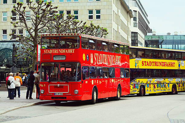 Hamburg, Germany - May, 14th 2011: Two sights seeing buses different companies ready for city tour at stop of square Rathausmarkt in free and Hanseatic city Hamburg in Germany. Some people still enter buses which are full of tourists. City hall is to left side in front of buses. In background are office and shoping buildings.